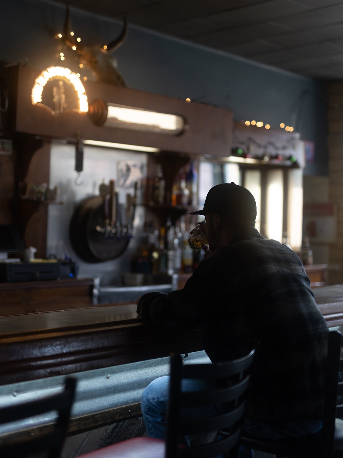 Kalen Mxrcus silhouette at a bar with bull skull and lights